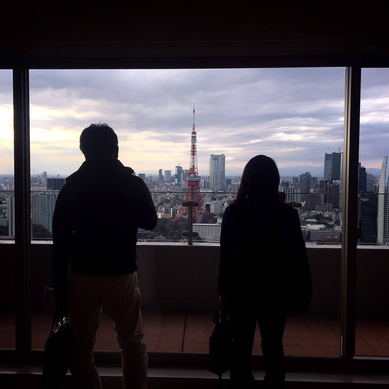 室内から東京タワーを眺める男女